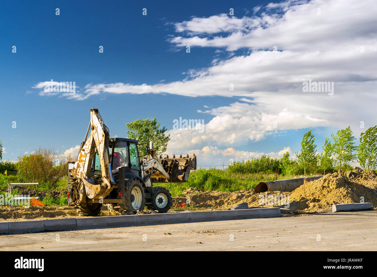 Trattore con benna esegue lavori di scavo. Costruzione di alta velocità tangenziale intorno Krasnoe Selo, San Pietroburgo. Macchina pesante attrezzatura fo Foto Stock