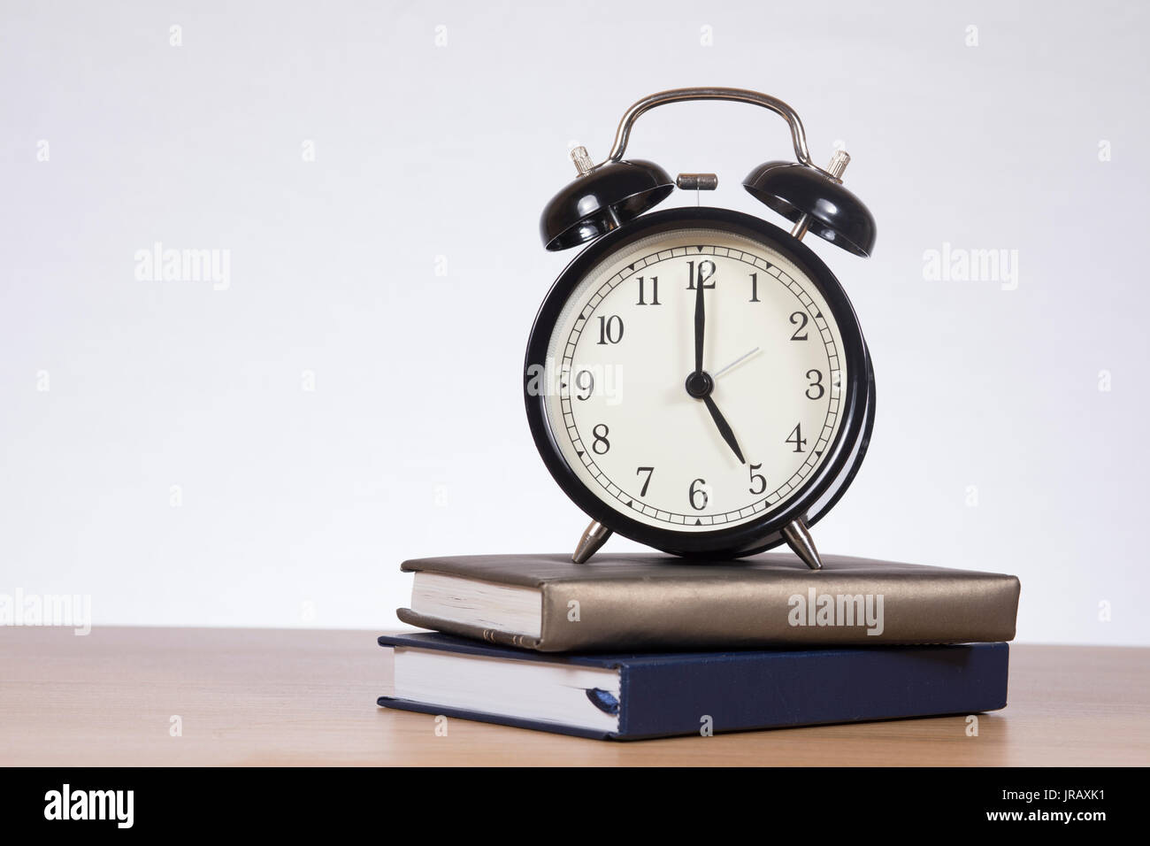 Retrò tipo campana orologio sveglia con il tempo impostato su cinque su libri impilati da un ufficio, business o a scuola, concettuale della casa del tempo con lo spazio di copia Foto Stock