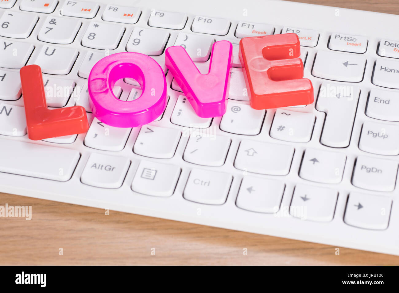 La parola amore del giocattolo di plastica le lettere sulla tastiera del computer sulla scrivania, close-up angolo alto concetto Foto Stock
