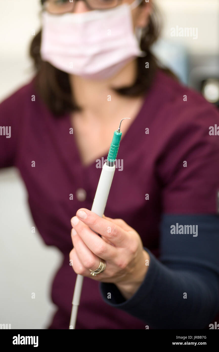 Igienista dentale tenendo in mano dentali scaler ad ultrasuoni usato per la pulizia dei denti Foto Stock