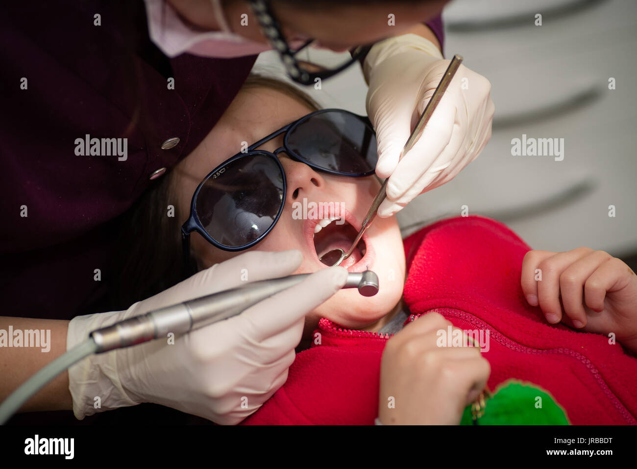 Bambino paziente avente denti puliti e lucidato e rimozione di decadimento da un igienista dentale in chirurgia dentale Foto Stock