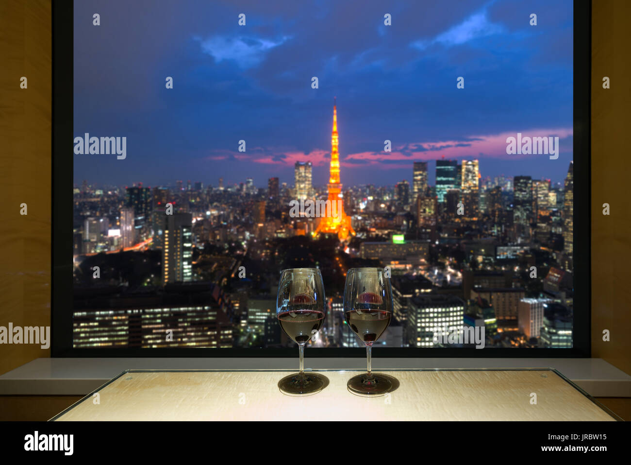 Primo piano di un bicchiere di vino rosso al davanzale, contro la notte Tokyo City View di urbano del cielo della città delle luci di sfocatura. Il Giappone. Foto Stock
