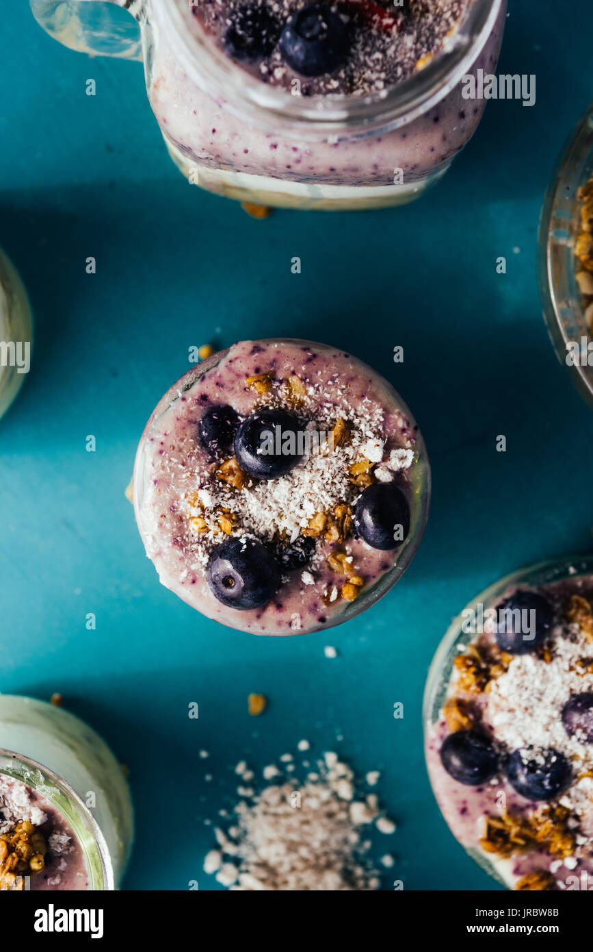 Vista dall'alto di una deliziosa colazione yogurt parfait fatta con yogurt fresco, strawbery smothie e ananas smoothie con strato di muesli e mirtillo come dec Foto Stock