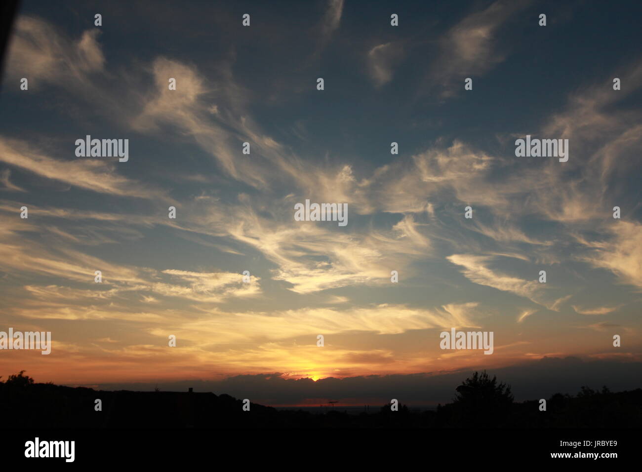 Tramonto spettacolare attraverso le nuvole wispy Foto Stock