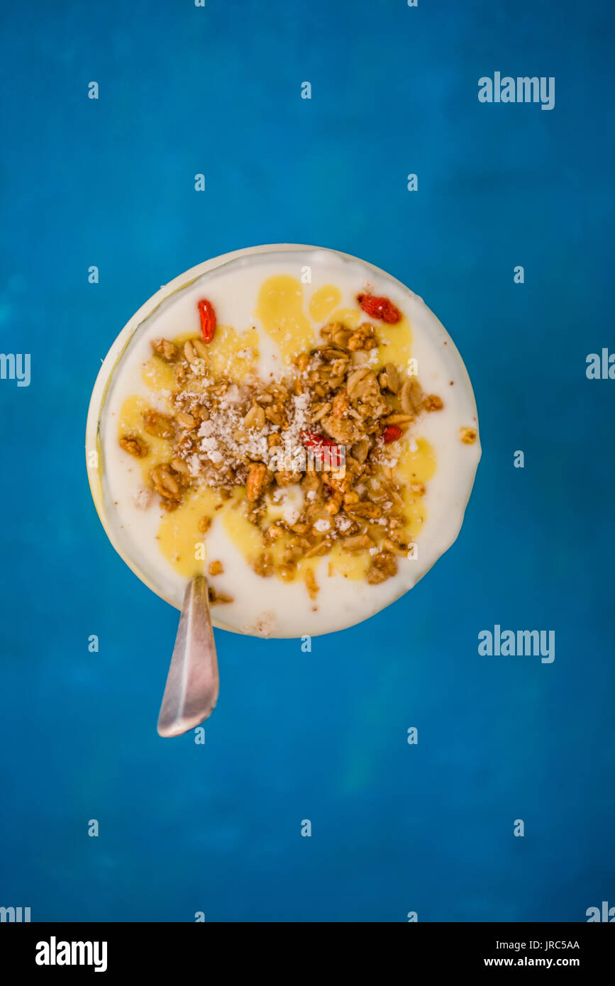 La deliziosa prima colazione yogurt parfait fatta con yogurt fresco, smothie mango e ananas smoothie con muesli e lo strato di decorazione su un blu woode arrugginito Foto Stock