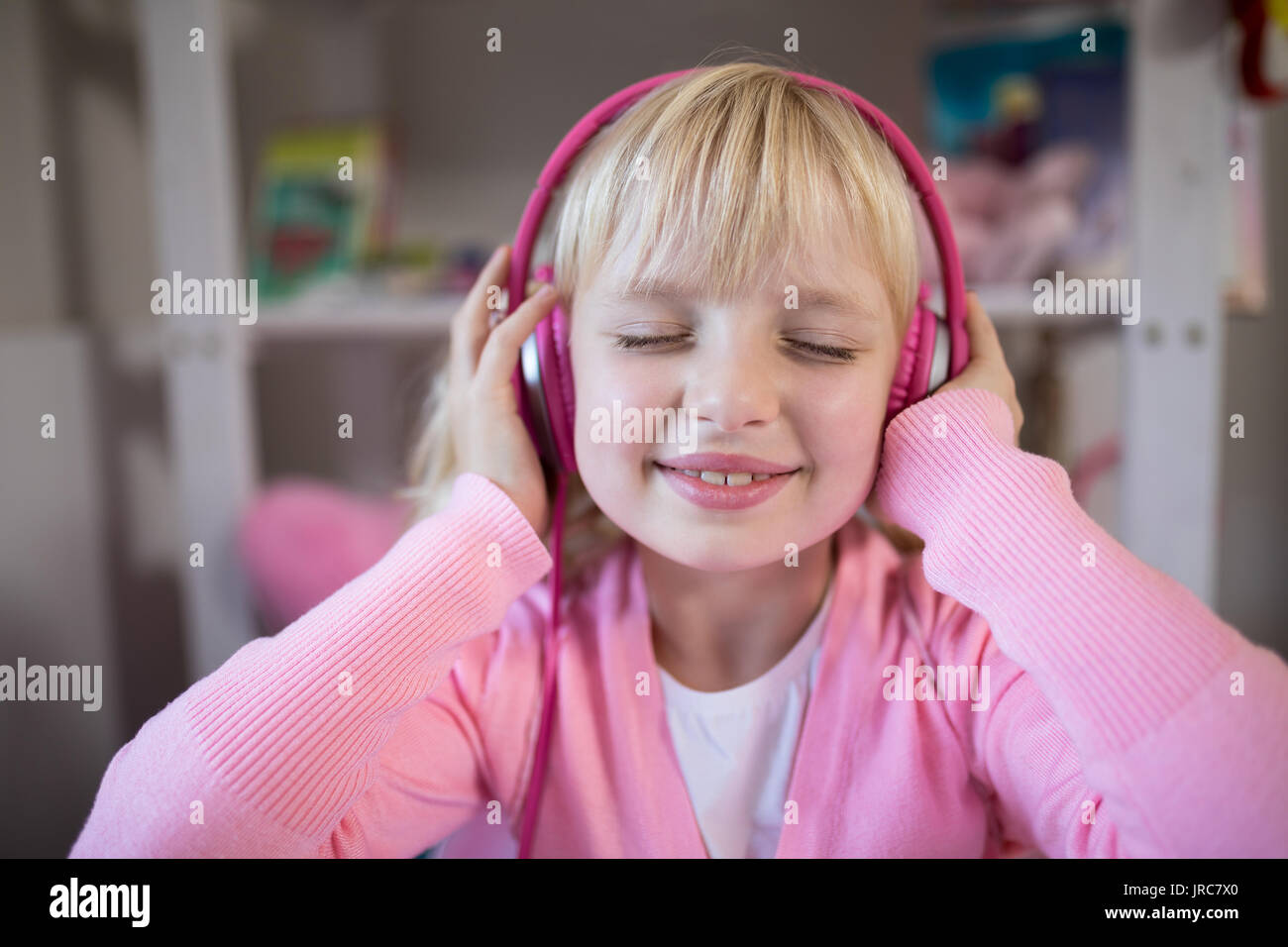 Close-up di Cute girl ascoltando le cuffie rosa Foto Stock