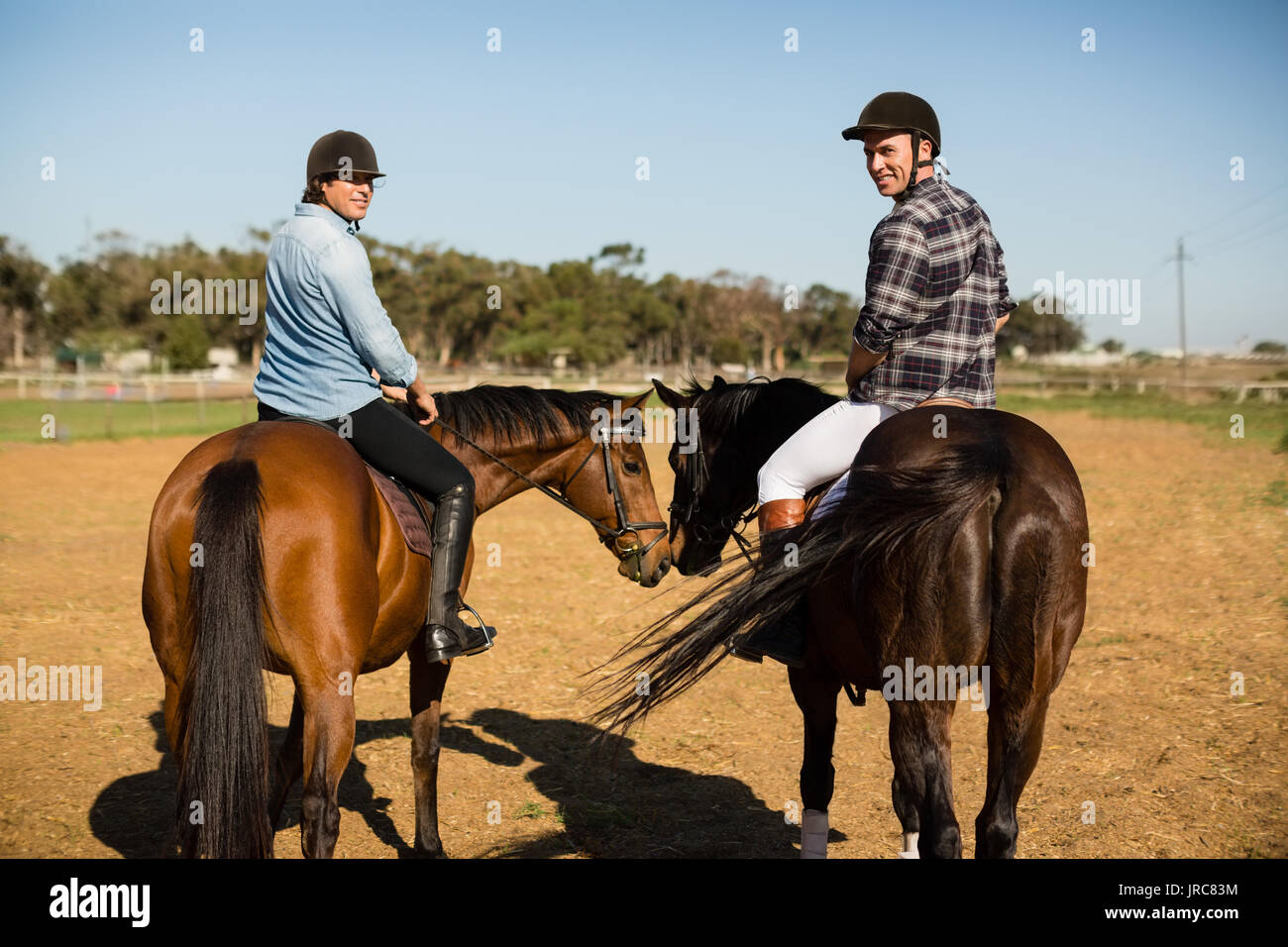 Due amici maschi a cavallo in un ranch in una giornata di sole Foto Stock