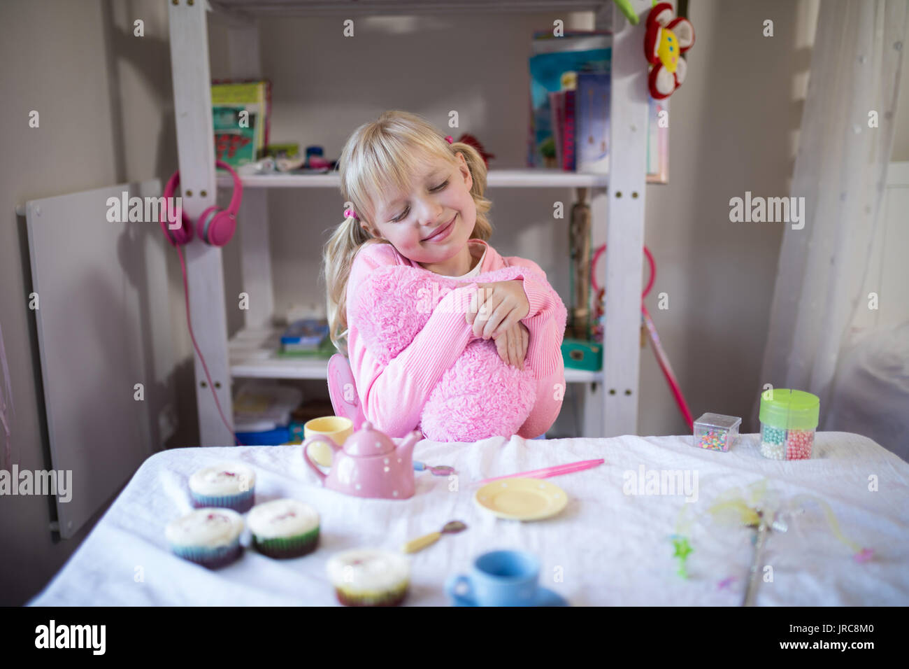 Close-up di Cute girl fantasticando mentre giocando con il giocattolo set da cucina Foto Stock