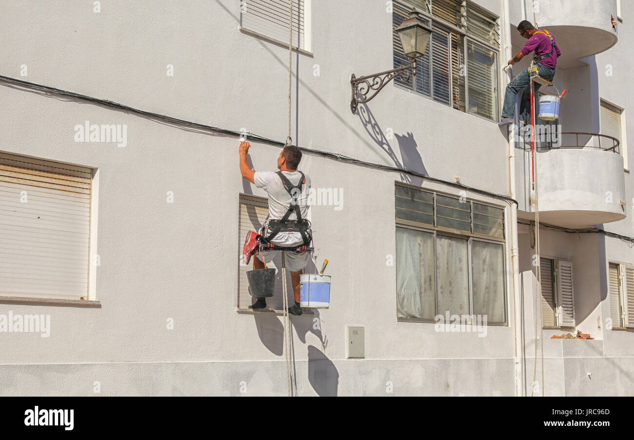 Due pittori in harnasses sbiancamento una parete in Portogallo Foto Stock