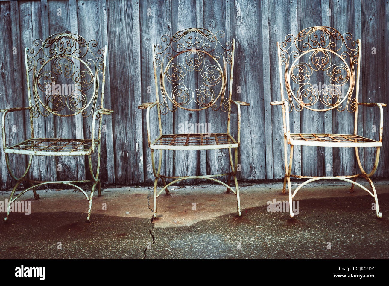 Tre vintage sedie in ferro al di fuori di una tettoia in legno Foto Stock
