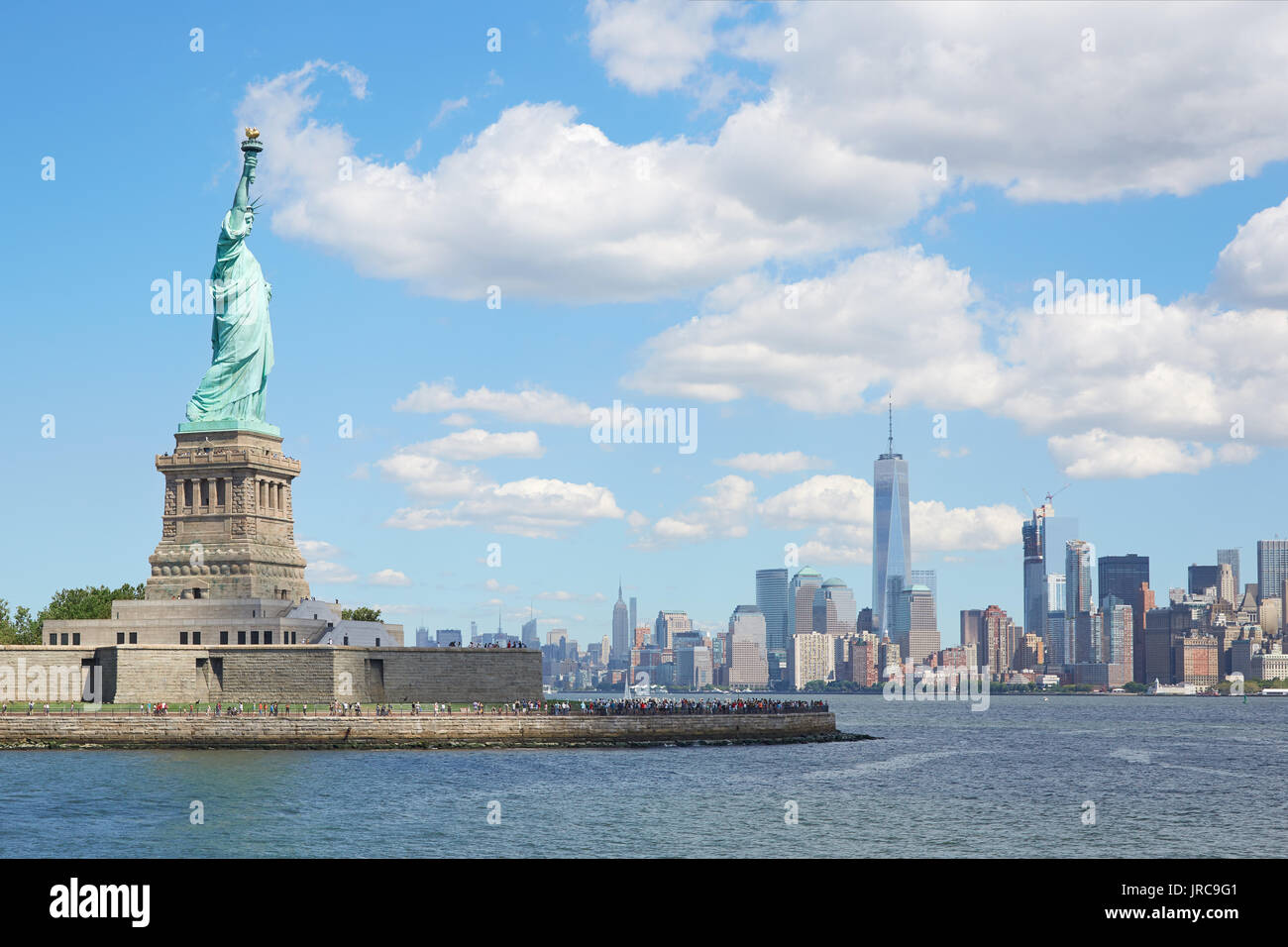 Statua di Liberty Island e New York skyline della città in una giornata di sole, il bianco delle nuvole Foto Stock