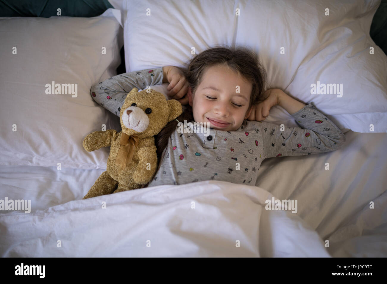 Ragazza dorme sul letto con Teddy bear in camera da letto a casa Foto Stock