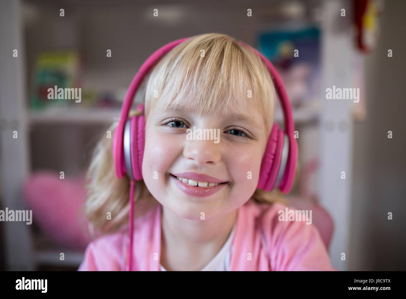 Sorridente ragazza carina ascoltando le cuffie rosa Foto Stock
