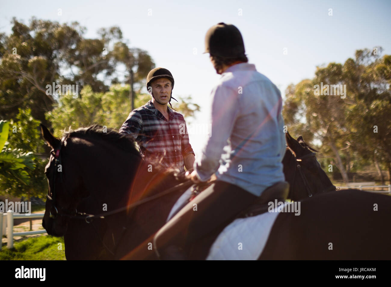 Due amici maschi a cavallo in un ranch in una giornata di sole Foto Stock