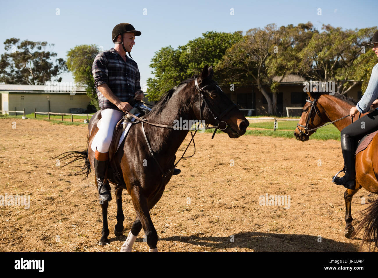 Due amici maschi a cavallo in un ranch in una giornata di sole Foto Stock