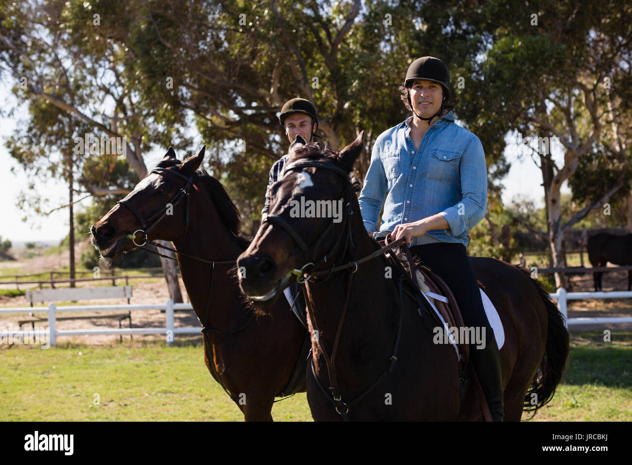 Due amici maschi a cavallo in un ranch in una giornata di sole Foto Stock