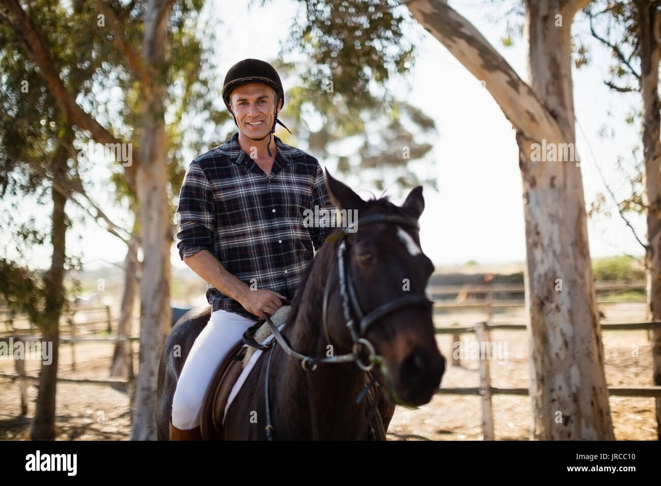 Uomo a cavallo nel ranch in una giornata di sole Foto Stock
