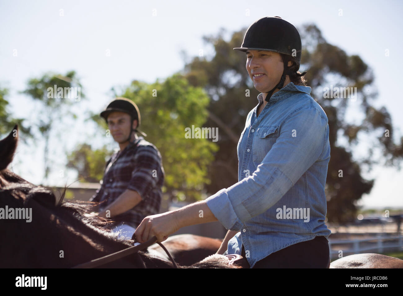 Due amici maschi a cavallo in un ranch in una giornata di sole Foto Stock