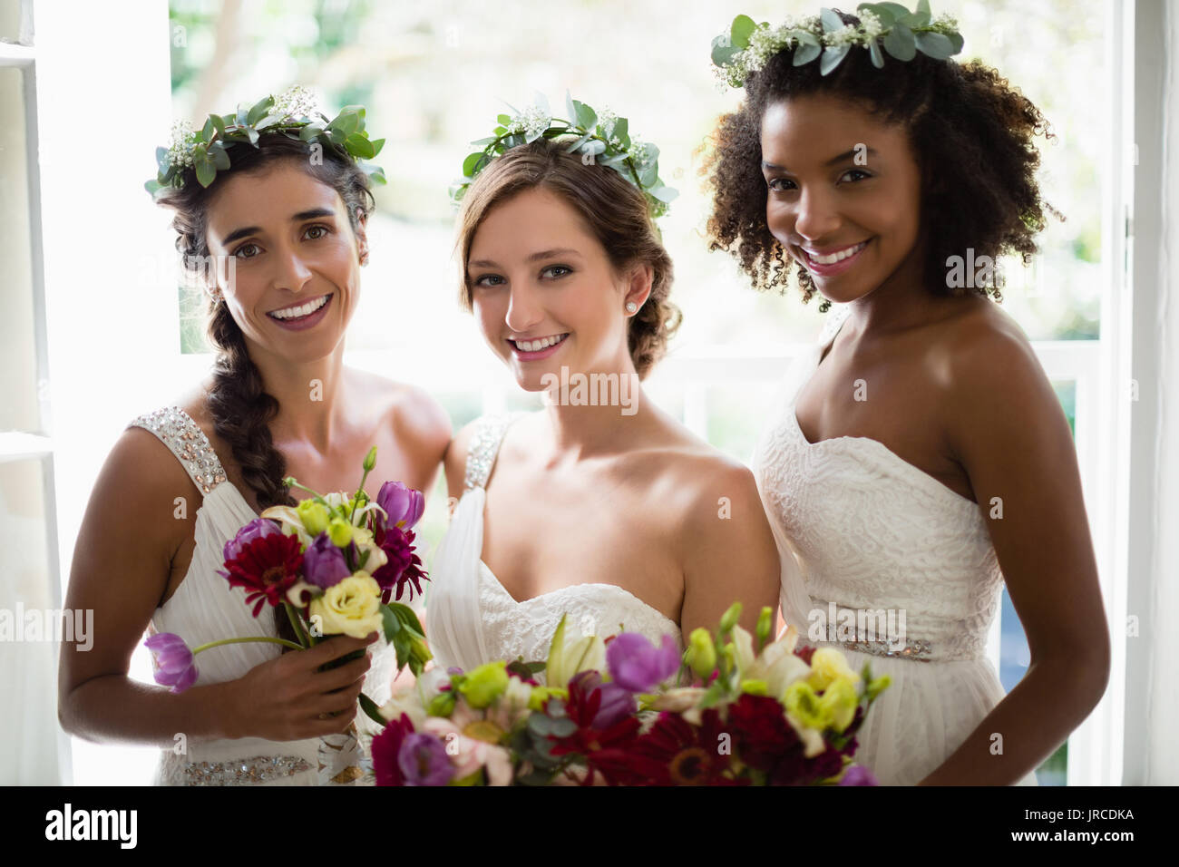 Ritratto di sposa e le sue damigelle hanno piedi con bouquet a casa Foto Stock