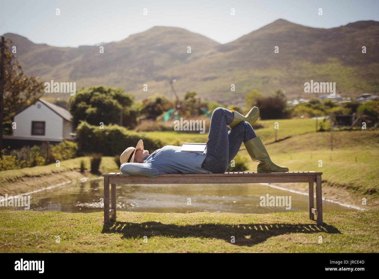 Senior donna che dorme sulla panchina del parco in una giornata di sole Foto Stock