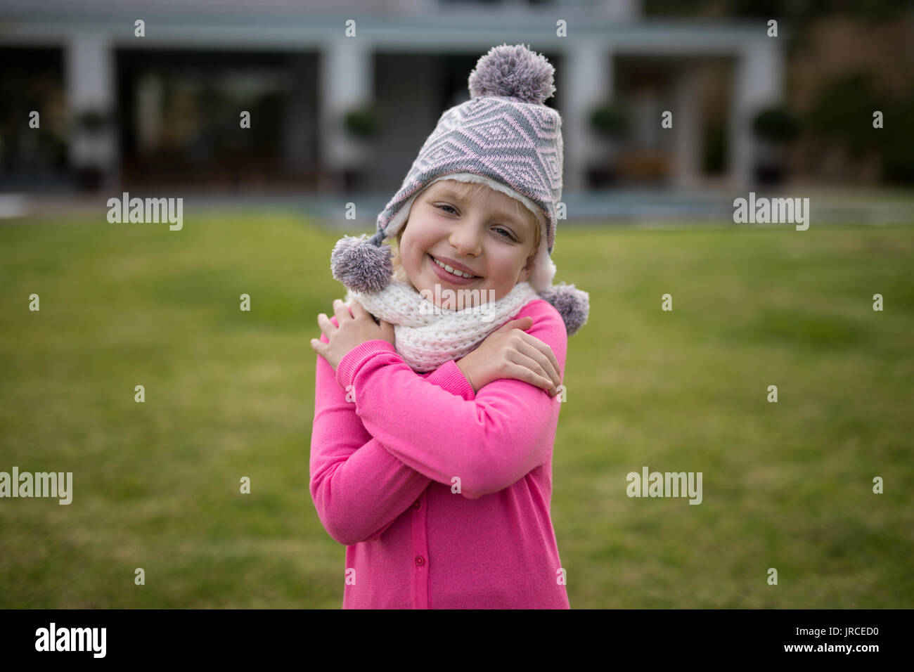 Sorridente ragazza carina in abiti caldi in piedi in giardino Foto Stock