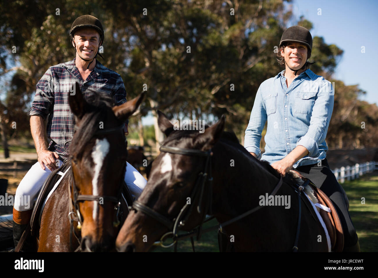 Due amici maschi a cavallo in un ranch in una giornata di sole Foto Stock