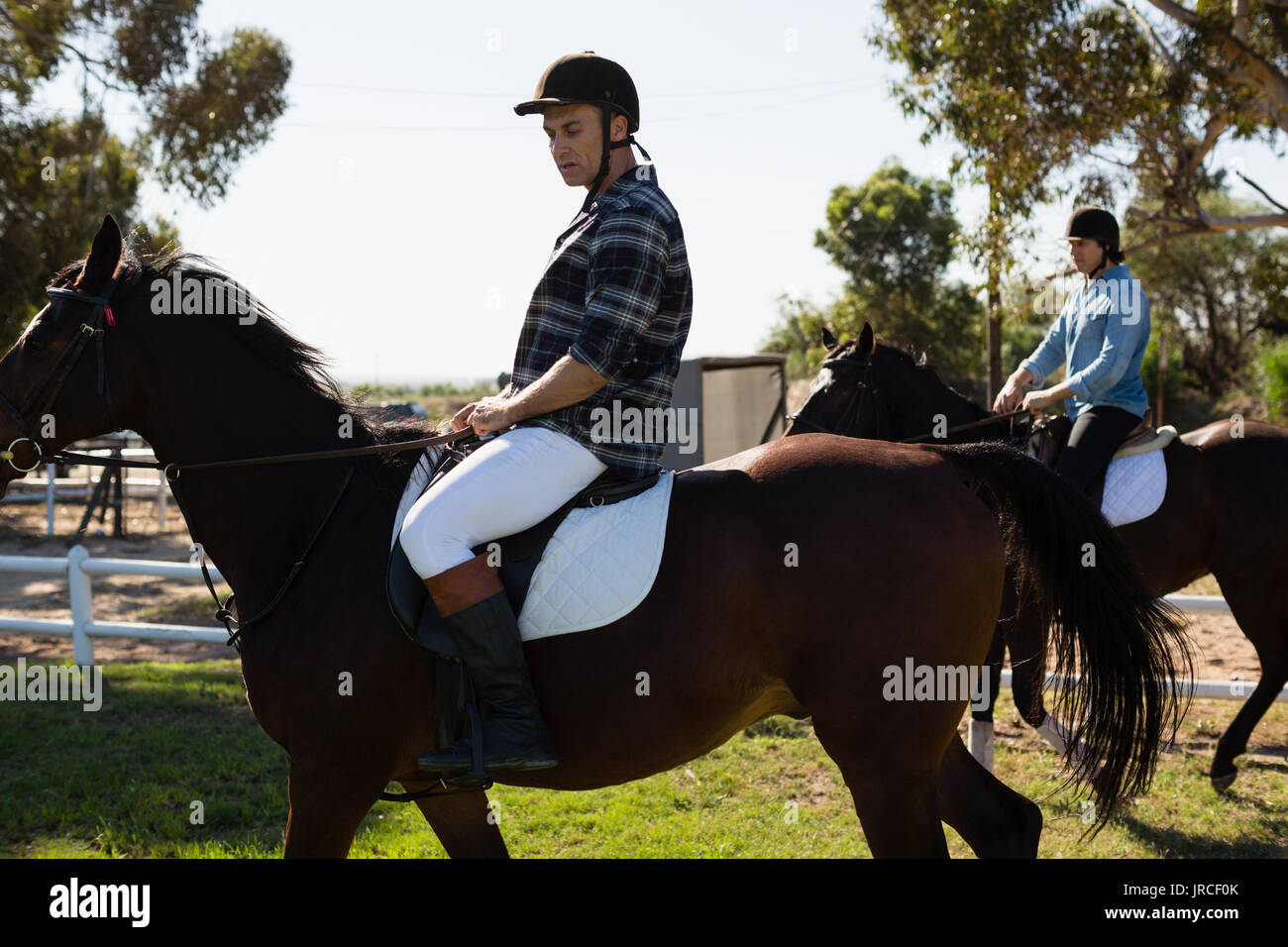 Due amici maschi a cavallo in un ranch in una giornata di sole Foto Stock