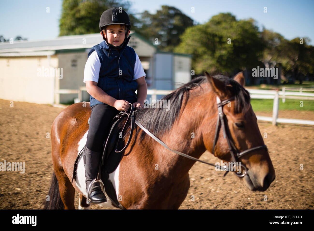 Ragazzo in sella ad un cavallo in un ranch in una giornata di sole Foto Stock