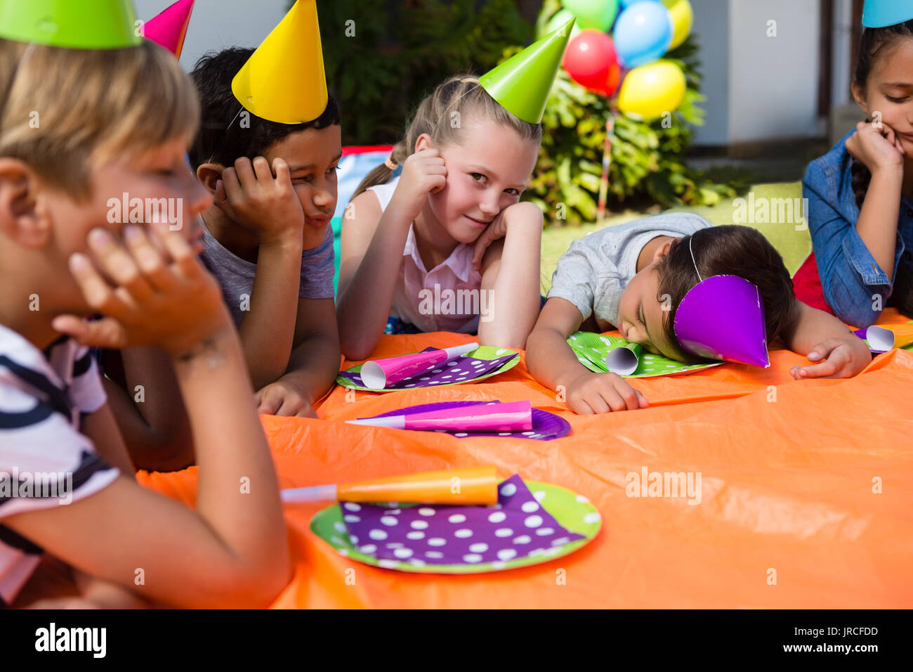 Ritratto di ragazza con stanco amici seduti a tavola durante la festa di compleanno Foto Stock