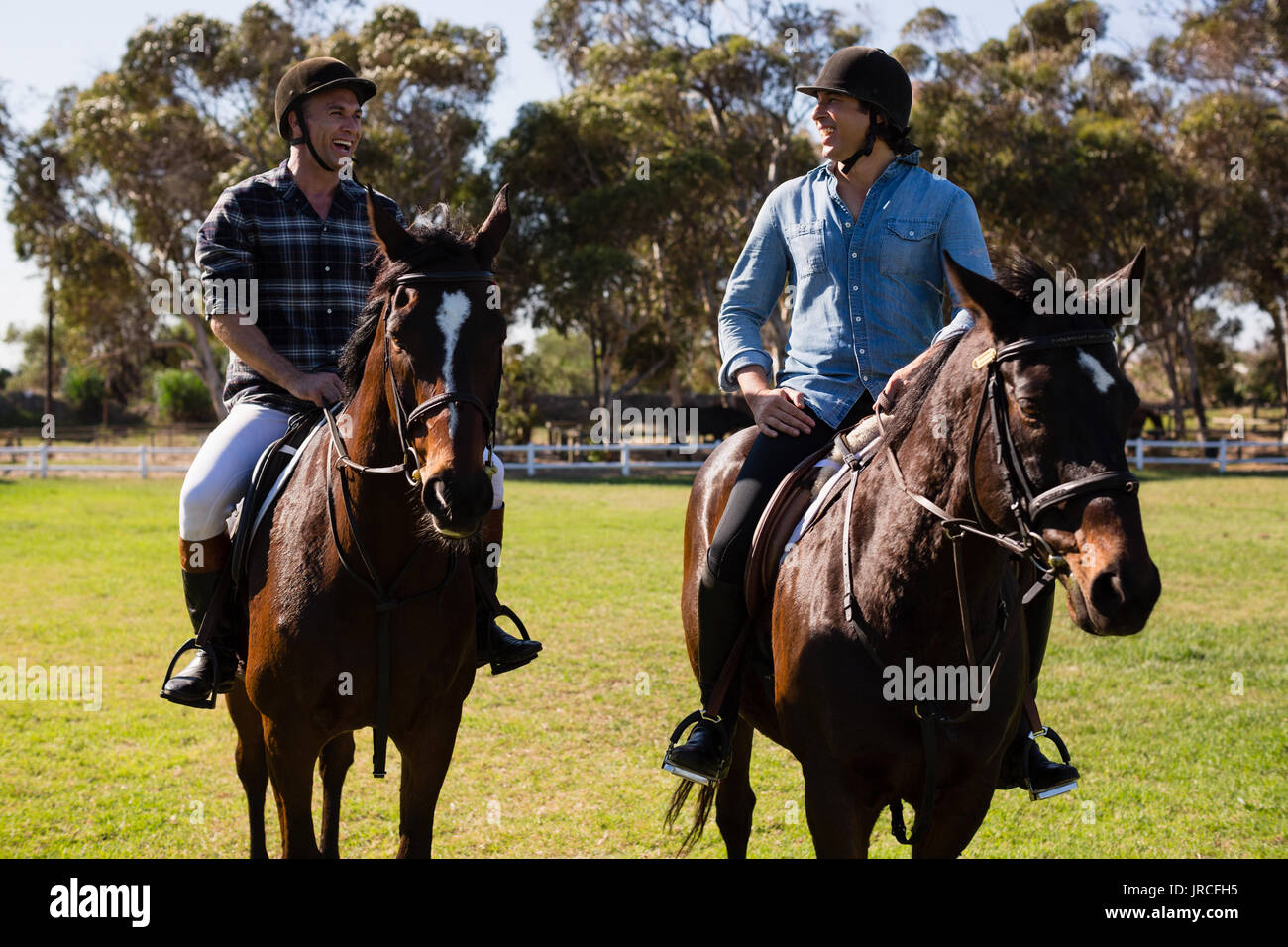 Due amici maschi a cavallo in un ranch in una giornata di sole Foto Stock