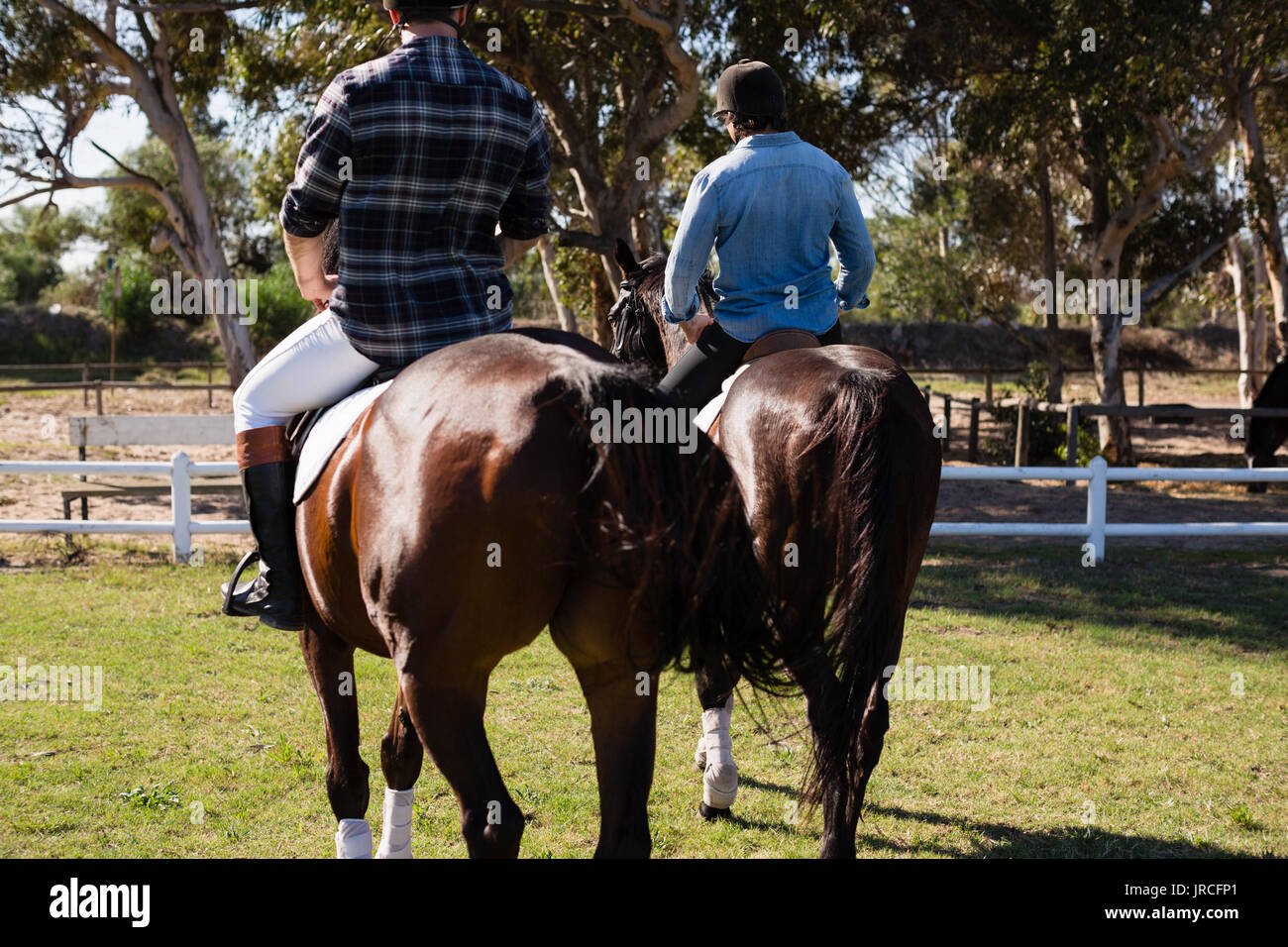 Due amici maschi a cavallo in un ranch in una giornata di sole Foto Stock