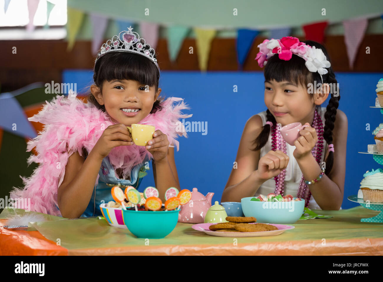 Cute ragazze avente il tè al tavolo durante la festa di compleanno a casa Foto Stock