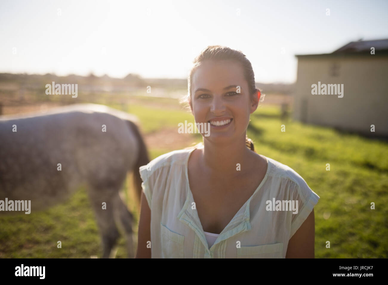 Ritratto di donna jockey in piedi sul campo al granaio Foto Stock