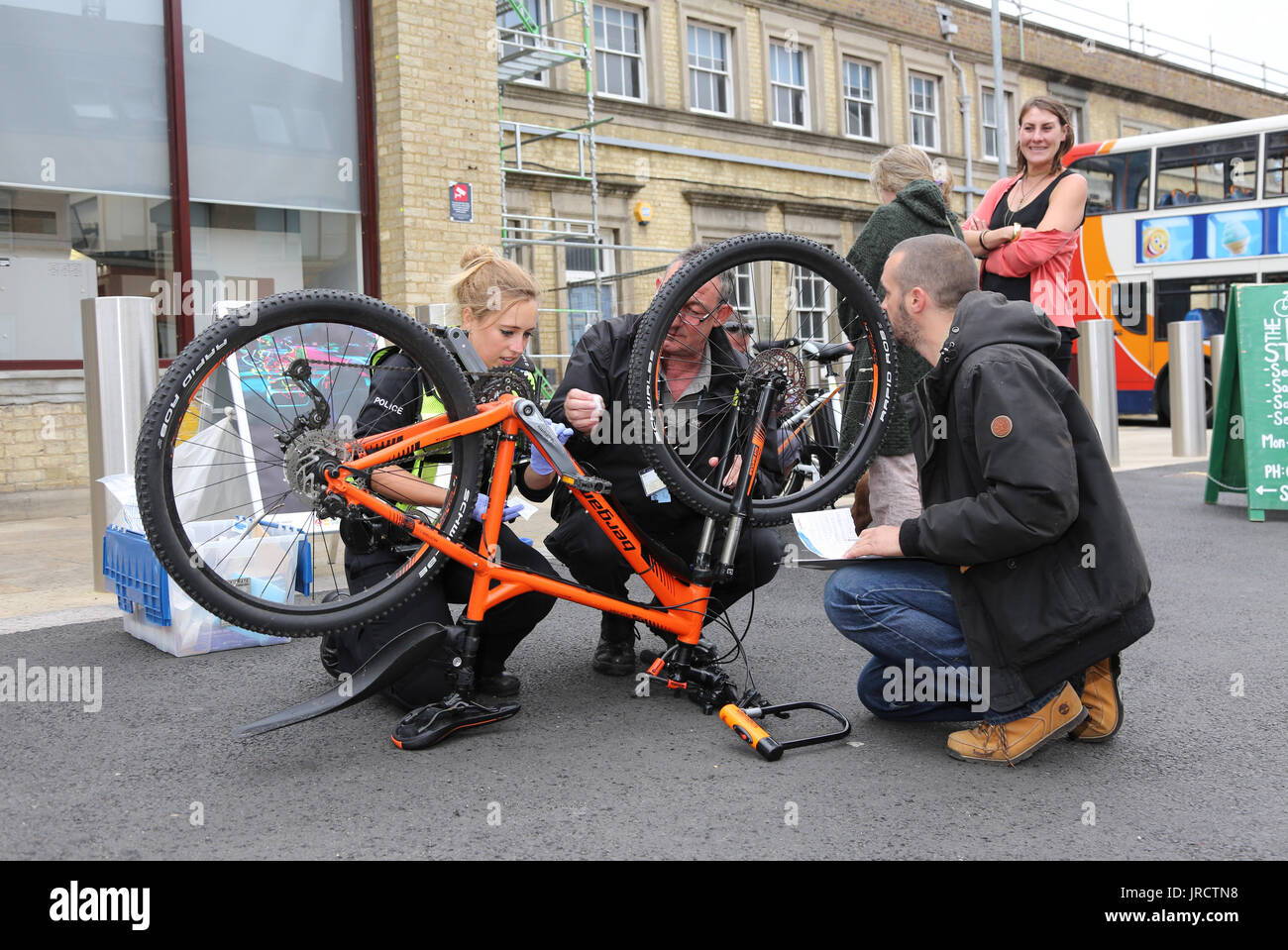 Una bicicletta registrazione evento in Cambridge, UK. Una femmina di funzionario di polizia contrassegni di sicurezza una bici mentre i dettagli sono registrati da un collega. Foto Stock