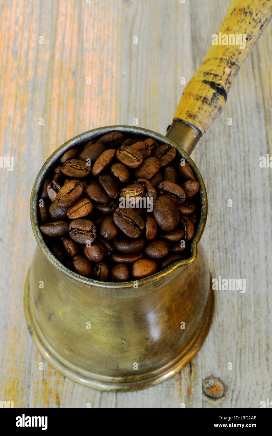 Vecchio caffè arabo pentola su sfondo di legno con fagioli Foto Stock