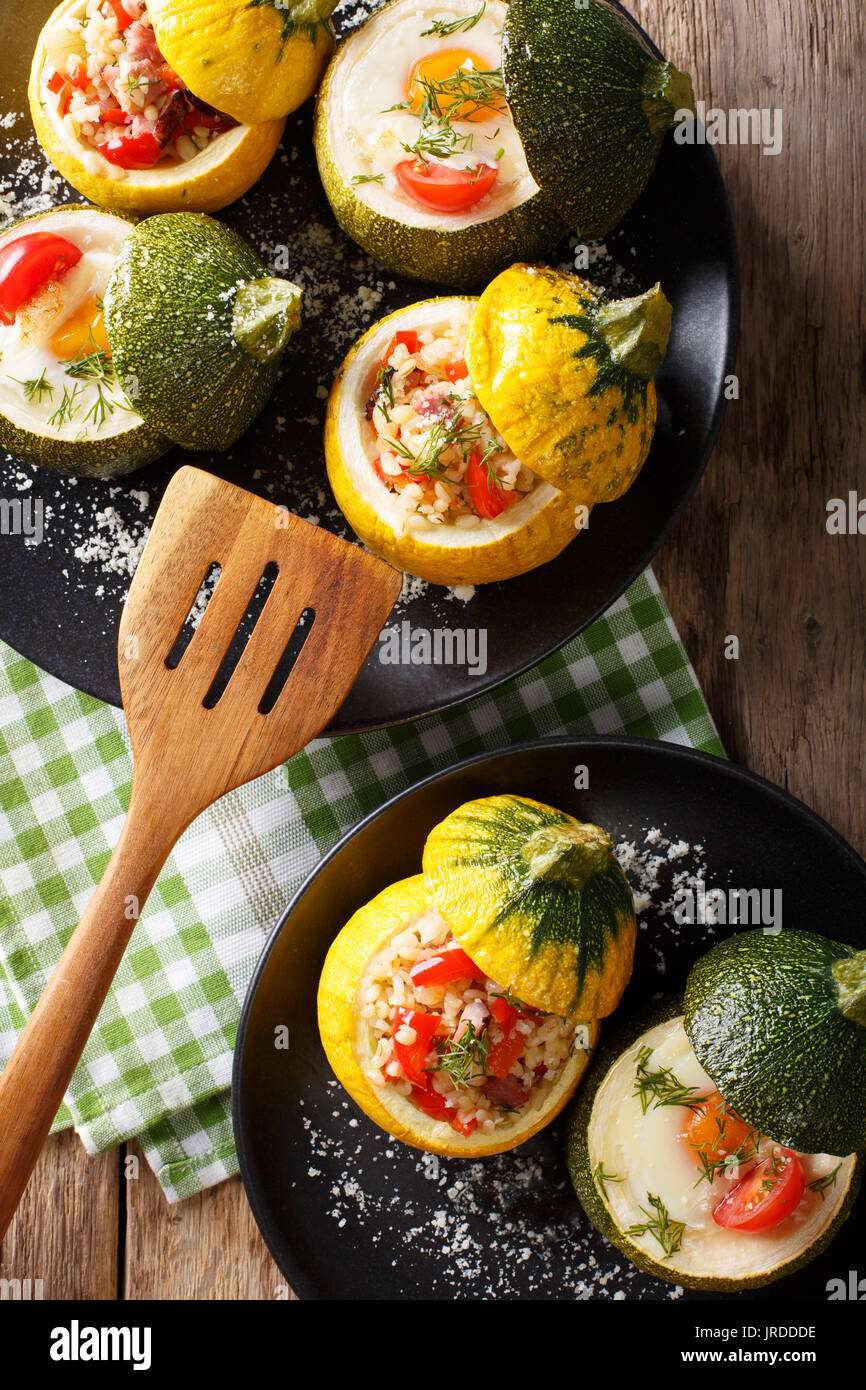 Giallo zucchini cotto con bulgur e carni e verde zucchine ripiene con uovo e pomodori close-up su una piastra. Vista verticale da sopra Foto Stock