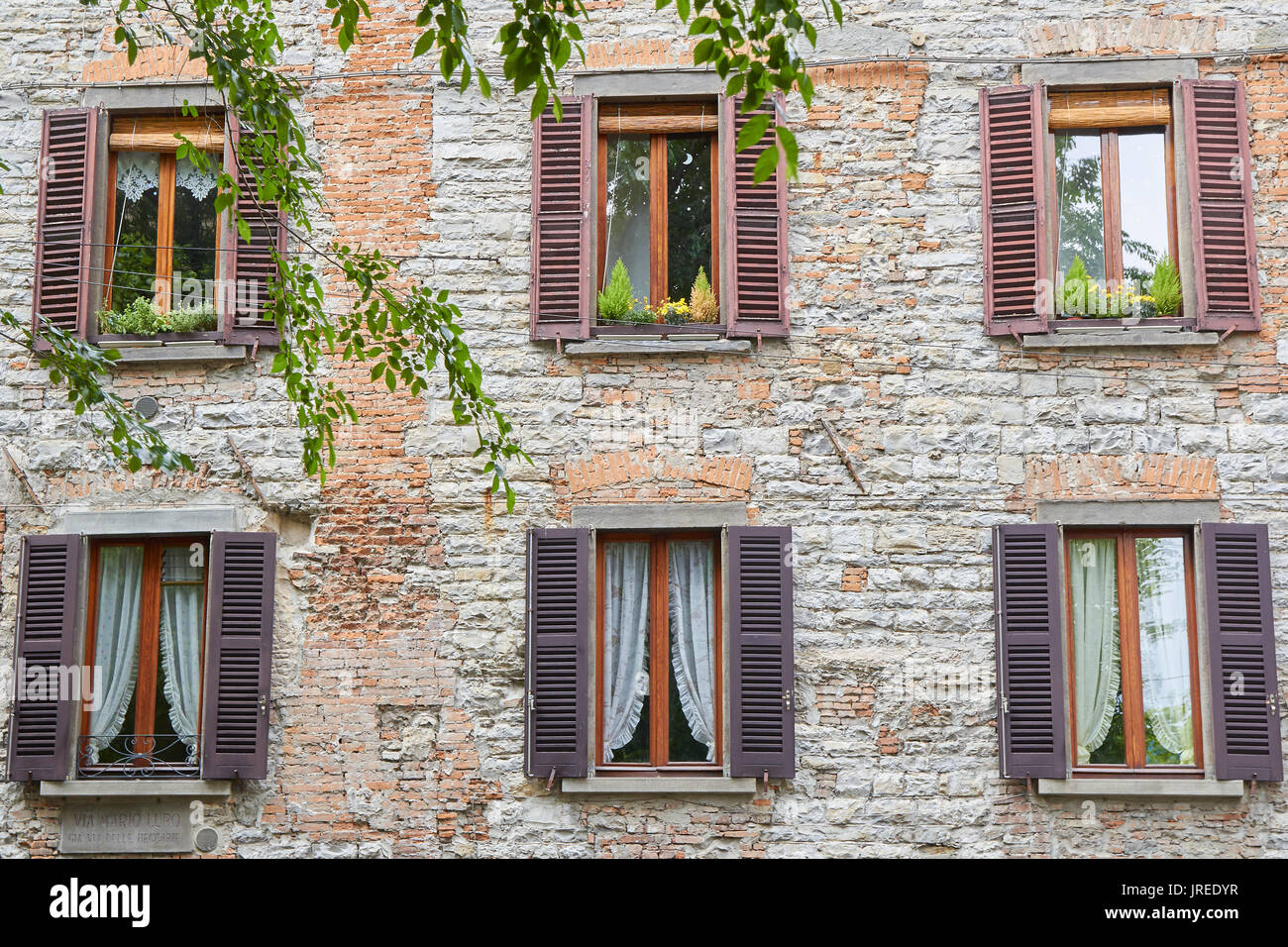 Sei finestre di legno su una facciata di mattoni in una strada della città di Bergamo (Italia) Foto Stock