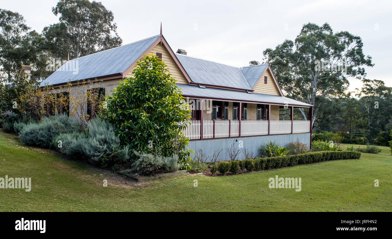 Australian coloniale di mattoni di pietra arenaria casa cottage con veranda, stagno per tetti e circondato da un giardino con alberi Foto Stock