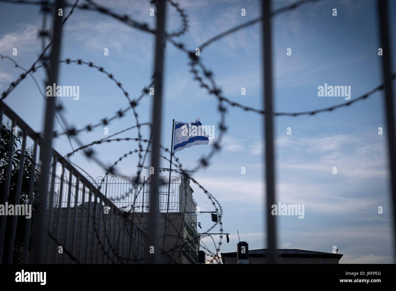 La bandiera Israeliana sorvola barricate di reticolati di filo spinato, un fin troppo comune in vista della/Palestinese conflitto israeliano Foto Stock