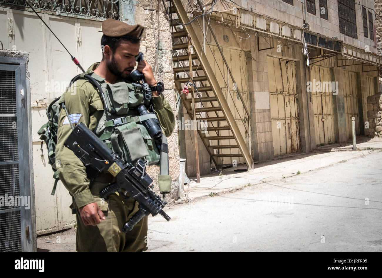 Soldato israeliano a guardia di un ex bustiling Hebron Market street ora chiusa ai palestinesi a causa di una terra grab di 850 coloni israeliani nelle vicinanze Foto Stock