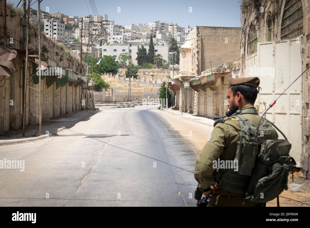 Soldato israeliano a guardia di un ex bustiling Hebron Market street ora chiusa ai palestinesi a causa di una terra grab di 850 coloni israeliani nelle vicinanze Foto Stock