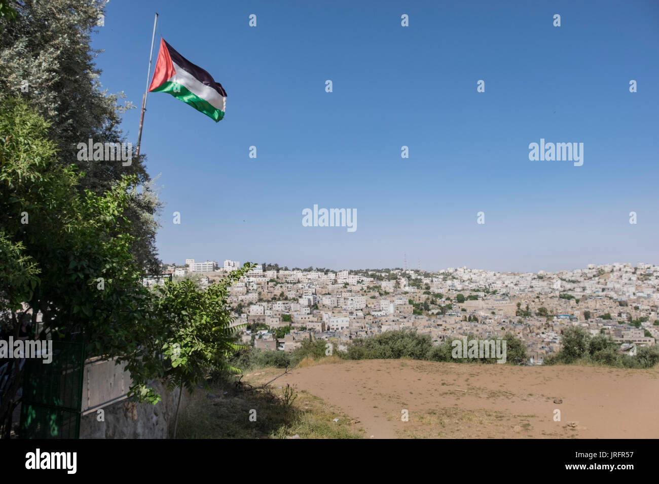Una vista del centro della città in conflitto di Hebron come visto da un quartiere palestinese che si affaccia con una bandiera palestinese battenti provocatoriamente Foto Stock