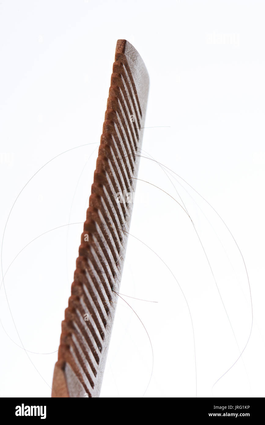 Pettine di legno con i capelli scuri strand isolati su sfondo bianco Foto Stock