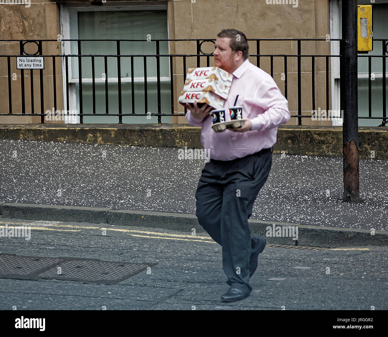 Uomo grasso pranzo attraversamento strada sovraccaricato con cibo spazzatura obesi lavoratore di ufficio KFC Pepsi Glasgow Scozia Scotland Foto Stock