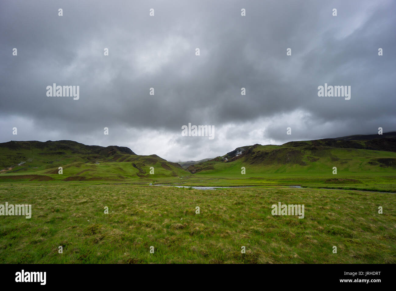 Islanda - fiume che scorre fra il verde delle montagne vulcaniche Foto Stock