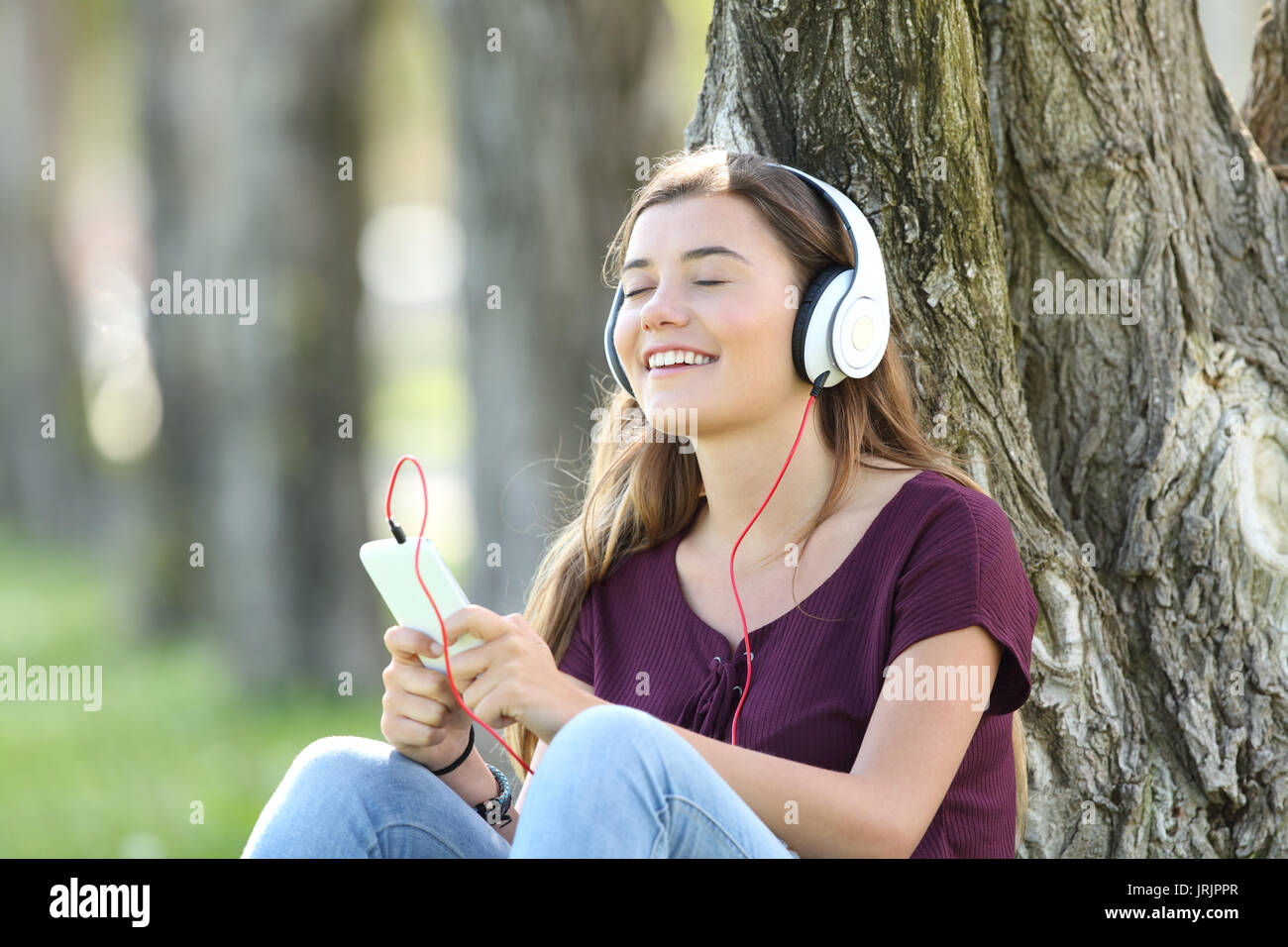 Unica sensazione teen la musica on line seduto sull'erba all'esterno in un parco Foto Stock