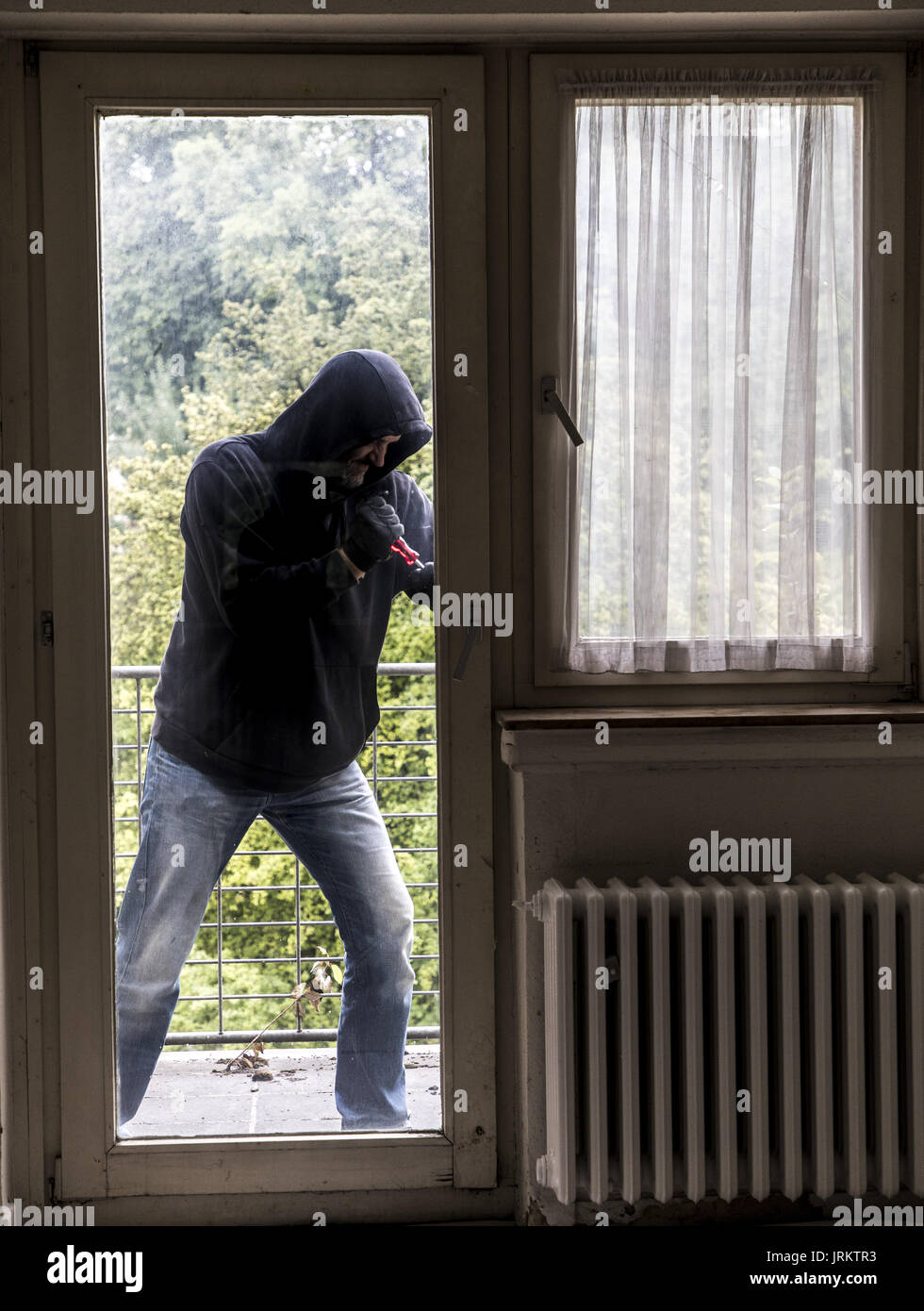 Immagine di simbolo, Appartamento antifurto, ladro tenta di rompere in un appartamento, la rottura di un vetro con l'attrezzo, Foto Stock
