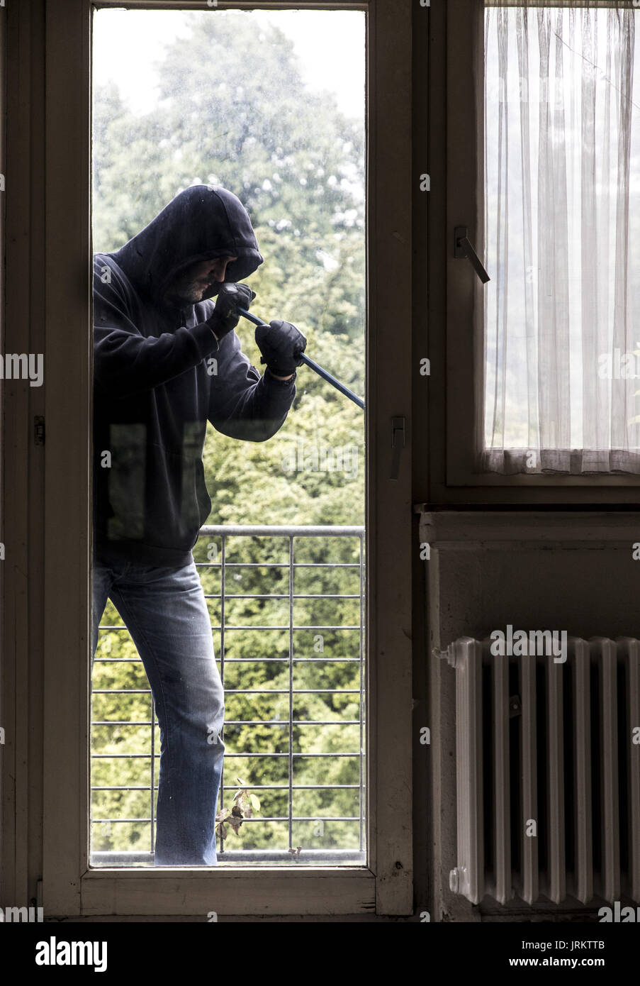 Immagine di simbolo, Appartamento antifurto, ladro tenta di rompere in un appartamento, la rottura di un vetro con l'attrezzo, Foto Stock