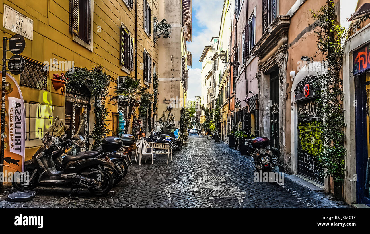 Il pittoresco stretto back street nella sezione di Trastevere di Roma Italia con negozi e moto parcheggiate Foto Stock