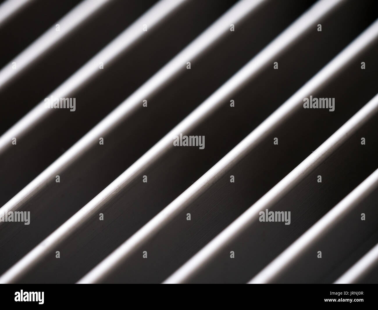 Close-up di alluminio griglia di copertura con il pattern di linee diagonali in ombra e luce, in bianco e nero Foto Stock